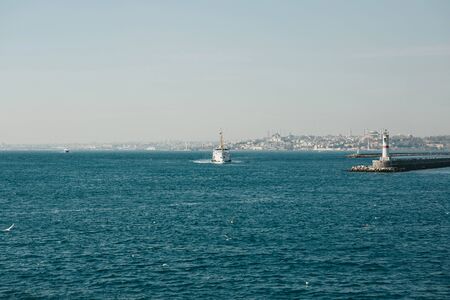Beautiful view of the ferry sailing along the Bosphorus and the lighthouse against the backdrop of...