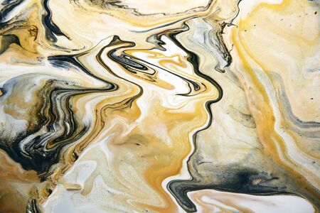 Acrylic paint fluid in trend black and gold with yellow color mix background.の写真素材