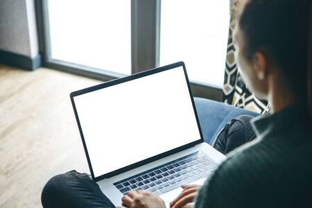 Girl at home uses laptop mockup. Modern technology in everyday life. Blank white screen place for text or template.の写真素材