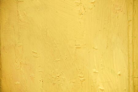 Bright yellow old ragged wall closeup backgroundの写真素材