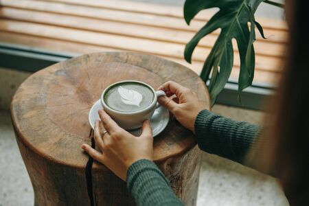 Girl drinks aromatic fresh and healthy green matcha latte tea in a cafe.の写真素材