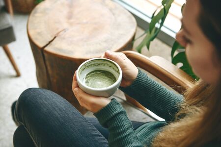 Girl drinks aromatic fresh and healthy green matcha latte tea in a cafe.の写真素材