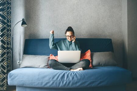 A girl works from home or a student is studying from home or a freelancer. She uses a laptop and a phone.の写真素材