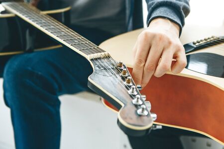 A student or guitarist tunes a guitar to play it.の写真素材