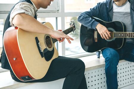 Learning to play the guitar. The teacher explains to the student the basics of playing the guitar. Individual home schooling or extracurricular lessons.の写真素材