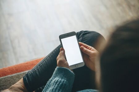 Girl at home uses a cell phone or mobile phone mockup. Modern technology in everyday life.の写真素材