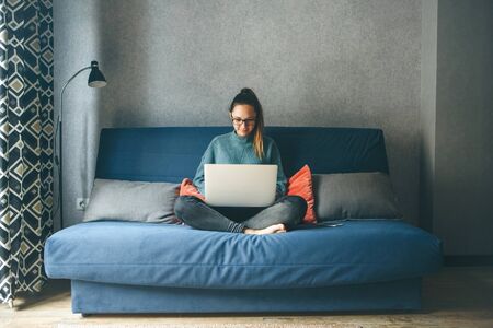Girl working on laptop from home or student studying from home or freelancer. Or she is watching a video or using the Internetの写真素材
