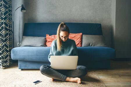 Girl working on laptop from home or student studying from home or freelancer. She is watching an online course or doing homework or surfing the net.の写真素材