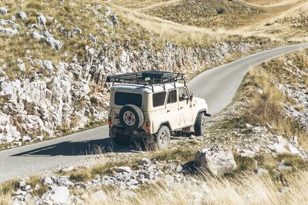 SUV rides on a road in the mountains. Extreme sport or road trip or adventure.の写真素材