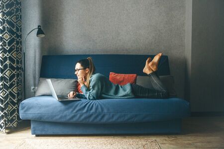 Girl working on laptop from home or student studying from home or freelancer. Or she is watching a video or using the Internetの写真素材