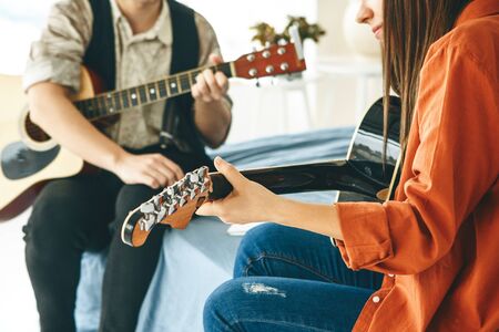 Learning to play the guitar. The teacher explains to the student the basics of playing the guitar. Individual home schooling or extracurricular lessons.の写真素材