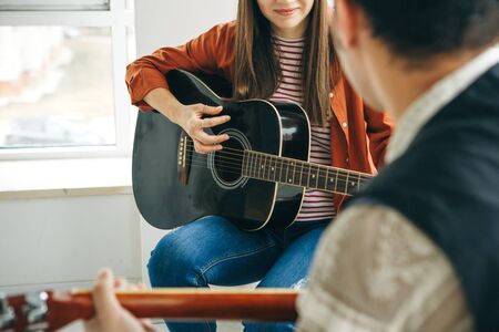 Learning to play the guitar. The teacher explains to the student the basics of playing the guitar. Individual home schooling or extracurricular lessons.の写真素材