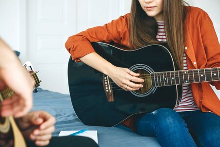 Learning to play the guitar. The teacher explains to the student the basics of playing the guitar. Individual home schooling or extracurricular lessons.の写真素材