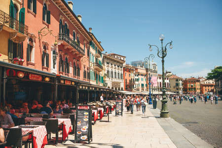 Italy, Verona, June 01, 2019: View of the city square with ancient European architecture with street cafes with many people.のeditorial素材