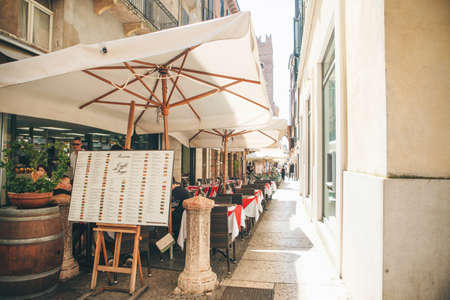 Italy, Verona, June 01, 2019: Street cafe among a narrow streetのeditorial素材