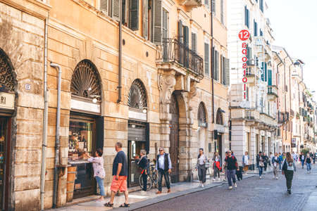 Italy, Verona, June 01, 2019: Locals and tourists walk or walk along a city street. They go sightseeing or go about their daily business.のeditorial素材