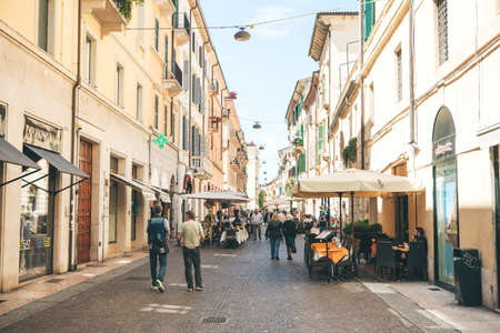 Italy, Verona, June 01, 2019: Typical street with cafes. Locals and tourists walk or walk along a city street. They go sightseeing or go about their daily business.のeditorial素材