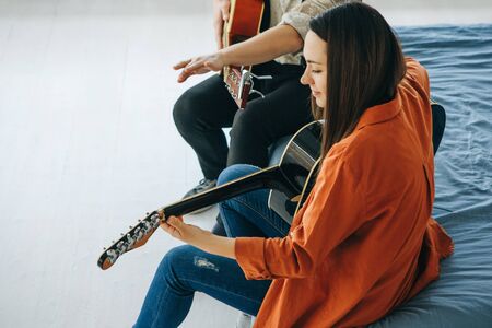 Learning to play the guitar. The teacher explains to the student the basics of playing the guitar. Individual home schooling or extracurricular lessons.の写真素材