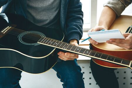 Learning to play the guitar. The teacher explains to the student the basics of playing the guitar. Individual home schooling or extracurricular lessons.の写真素材