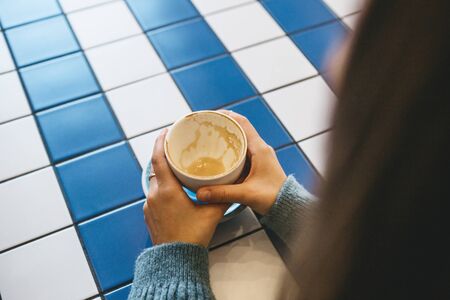 The girl is holding a cup with drunk coffee. Her meeting or coffee break ended.の写真素材