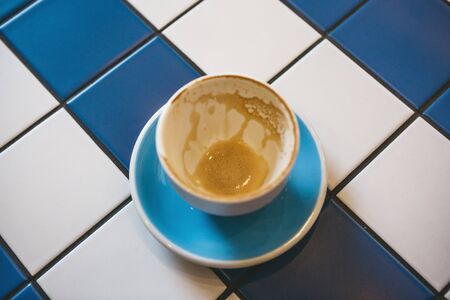 A cup of drunk coffee on a ceramic tile table. Concept for completing a meeting or coffee break.の写真素材