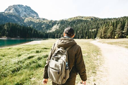 A tourist with a backpack is walking along a rural road against the background of a beautiful natural landscape in Montenegro.の写真素材