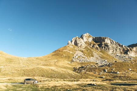 Beautiful natural landscape in Montenegro. Mountains against the blue sky. At the bottom of the frame is a car on the road. Road trip.の写真素材