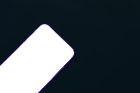 Frameless cell phone with blank white screen mockup on black background.の写真素材