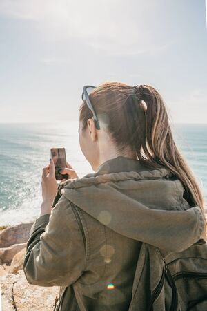 A tourist photographs a beautiful natural seascape on a cell phone or records video for memory.の写真素材