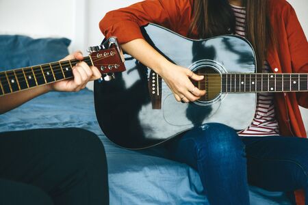 Learning to play the guitar. The teacher explains to the student the basics of playing the guitar. Individual home schooling or extracurricular lessons.の写真素材