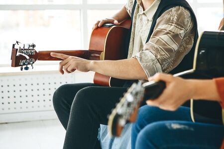 Learning to play the guitar. The teacher explains to the student the basics of playing the guitar. Individual home schooling or extracurricular lessons.の写真素材