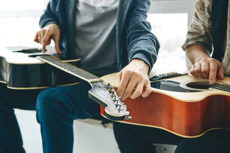 Learning to play the guitar. The teacher helps the student tune the guitar and explains the basics of playing the guitar. Individual home schooling or extracurricular lessons.の写真素材