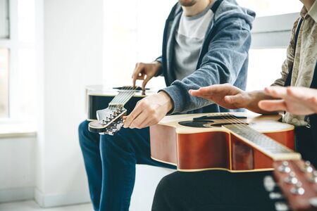 Learning to play the guitar. The teacher helps the student tune the guitar and explains the basics of playing the guitar. Individual home schooling or extracurricular lessons.の写真素材