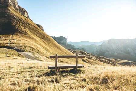 Wooden bench against the backdrop of a natural mountain landscape in autumn in the north of Montenegroの写真素材