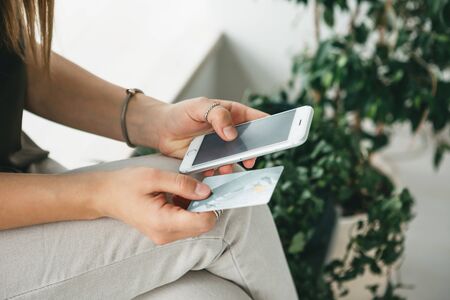 Online shopping. Girl with a cell phone and a credit card or a bank card in hands.の写真素材
