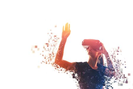 A girl in virtual reality glasses is pixelated or scattered into pixels. VR concept. Modern technologies.の写真素材