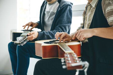 Learning to play the guitar. The teacher helps the student tune the guitar and explains the basics of playing the guitar. Individual home schooling or extracurricular lessons.の写真素材