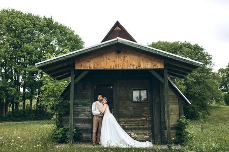 The bride and groom are standing next to the house. Rural or rustic sceneの写真素材