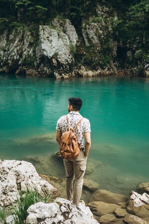 Tourist with a backpack on the background of a picturesque view of the river or lake. Tourist on a...