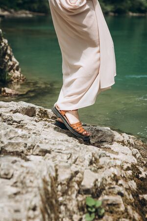 Close up of woman in dress and sandals by the river.の写真素材