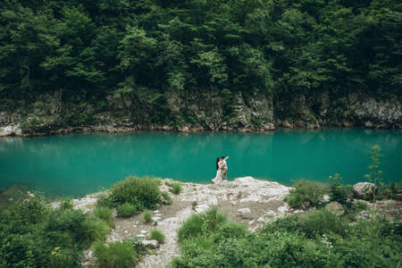 Young couple in the nature. A man hugs a woman on a background of a beautiful view of the river.の写真素材
