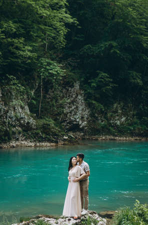 Young couple in the nature. A man hugs a woman on a background of a beautiful view of the river.の写真素材