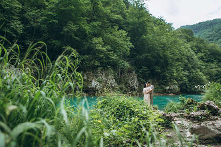 Young couple in the nature. A man hugs a woman on a background of a beautiful view of the river.の写真素材