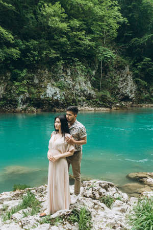 Young couple in the nature. A man hugs a woman on a background of a beautiful view of the river.の写真素材