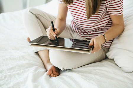 Girl digital artist draws with a stylus on a tablet or laptop. She is a student and is studying drawing or is this her professional occupation.の写真素材