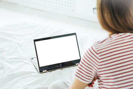 Girl at home uses laptop mockup. Modern technology in everyday life. Blank white screen place for text or template.の写真素材