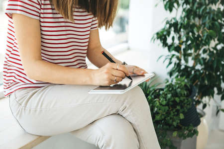 Girl digital artist draws with a stylus on the tablet. She is a student and is studying drawing or is this her professional occupation.の写真素材