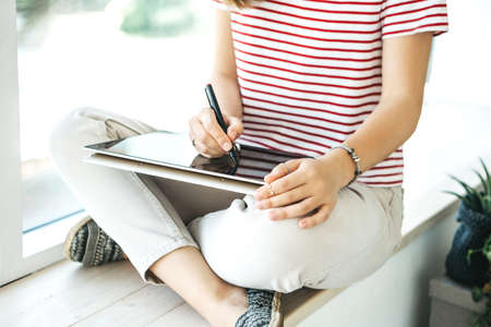Girl digital artist draws with a stylus on a tablet or laptop. She is a student and is studying drawing or is this her professional occupation.の写真素材