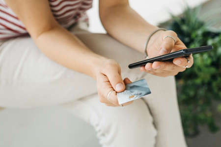 Online shopping. Girl with a cell phone and a credit card or a bank card in hands.の写真素材
