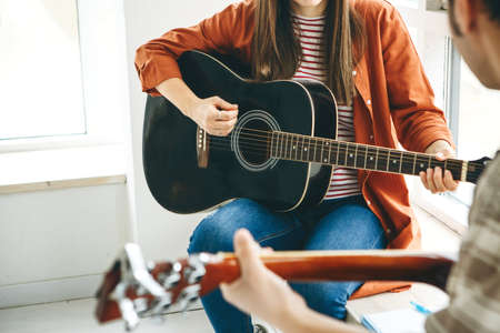 Learning to play the guitar. The teacher explains to the student the basics of playing the guitar. Individual home schooling or extracurricular lessons.の写真素材